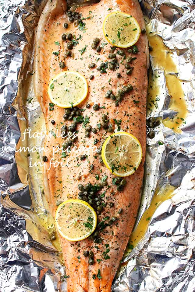 A large salmon filet garnished with lemon slices and capers.