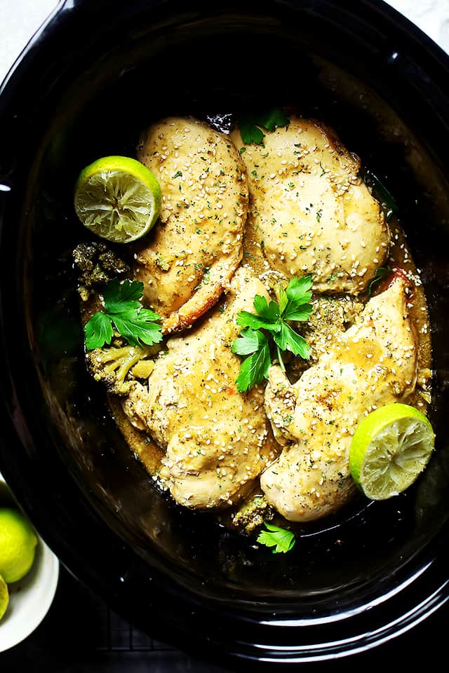 Overhead view of garlic lime chicken with fresh lime slices inside the slow cooker.