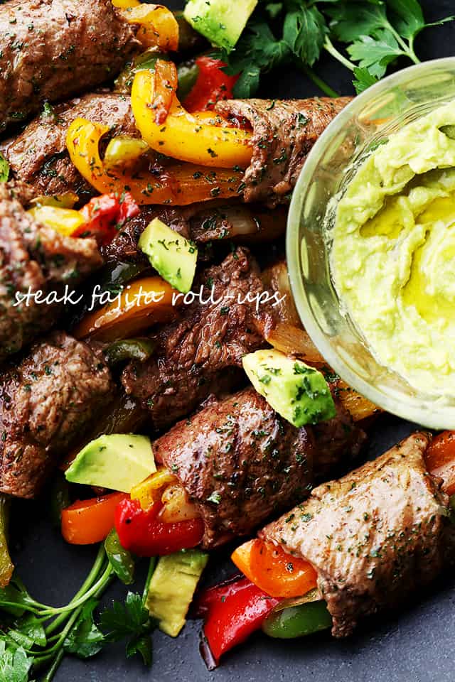 Steak Fajita Roll-Ups served on a black plate with guacamole on the side.