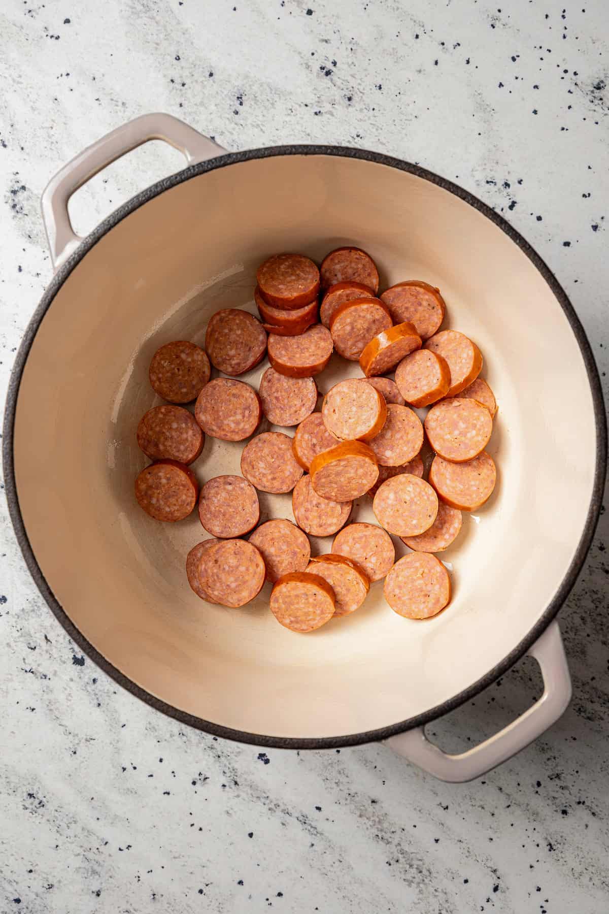 Andouille sausage slices in a large pot.