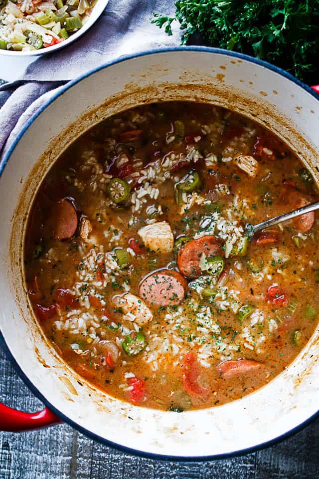 A pot with a spoon in it filled with homemade gumbo and rice