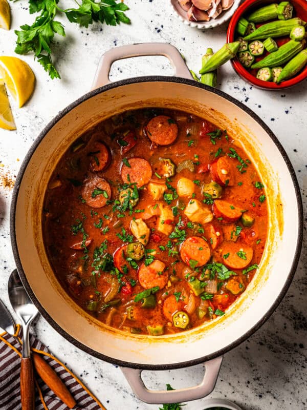 A pot of gumbo surrounded by small bowls of ingredients.