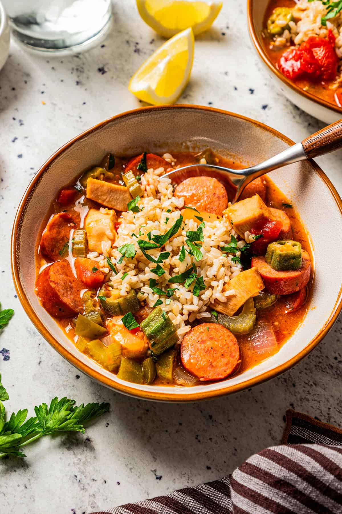 Chicken and sausage gumbo served in a bowl, with a spoon resting inside the bowl.