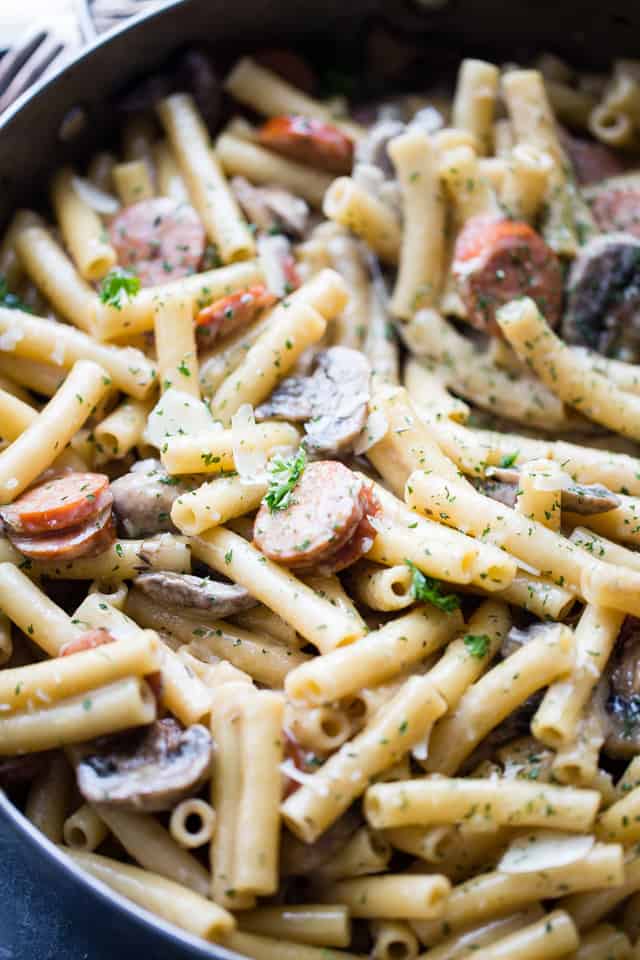 Close-up photo of tube-shaped pasta mixed with sausages and mushrooms.