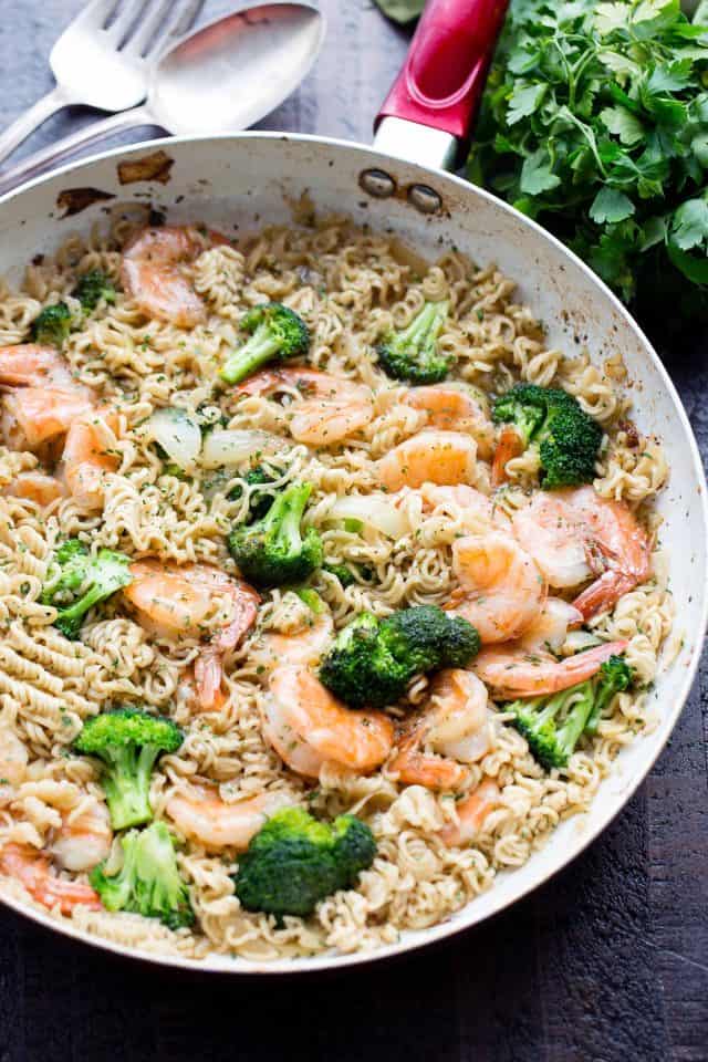 A skillet with ramen noodles, shrimp, and broccoli.