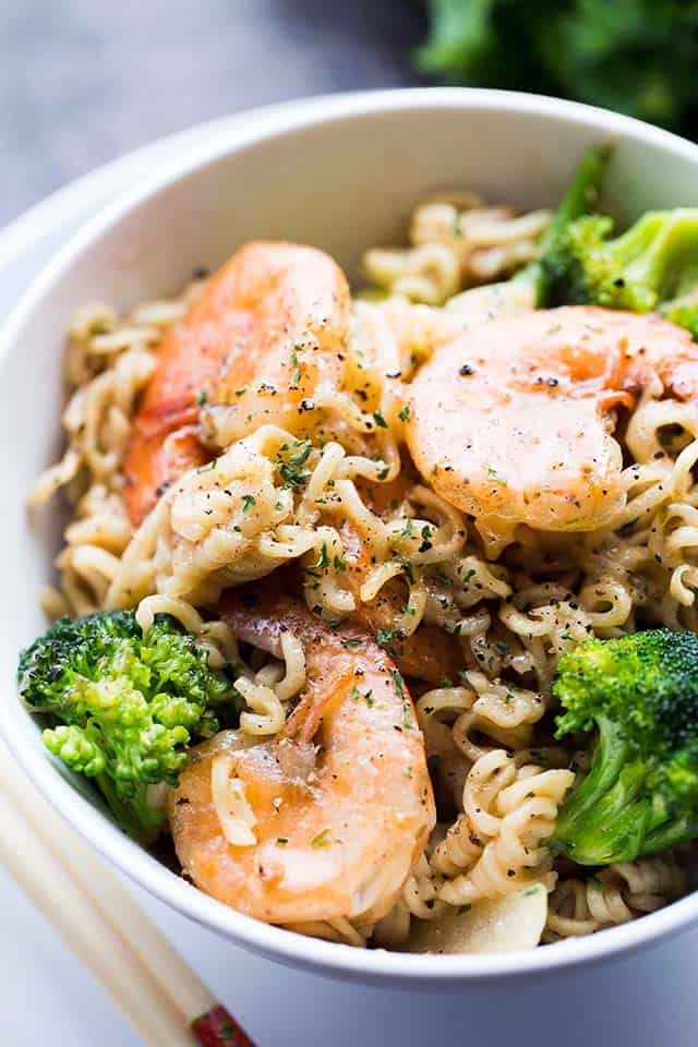 A bowl of ramen noodles with broccoli and shrimp.