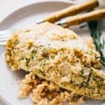 A lemon garlic tilapia filet served over a bed of risotto on a plate.
