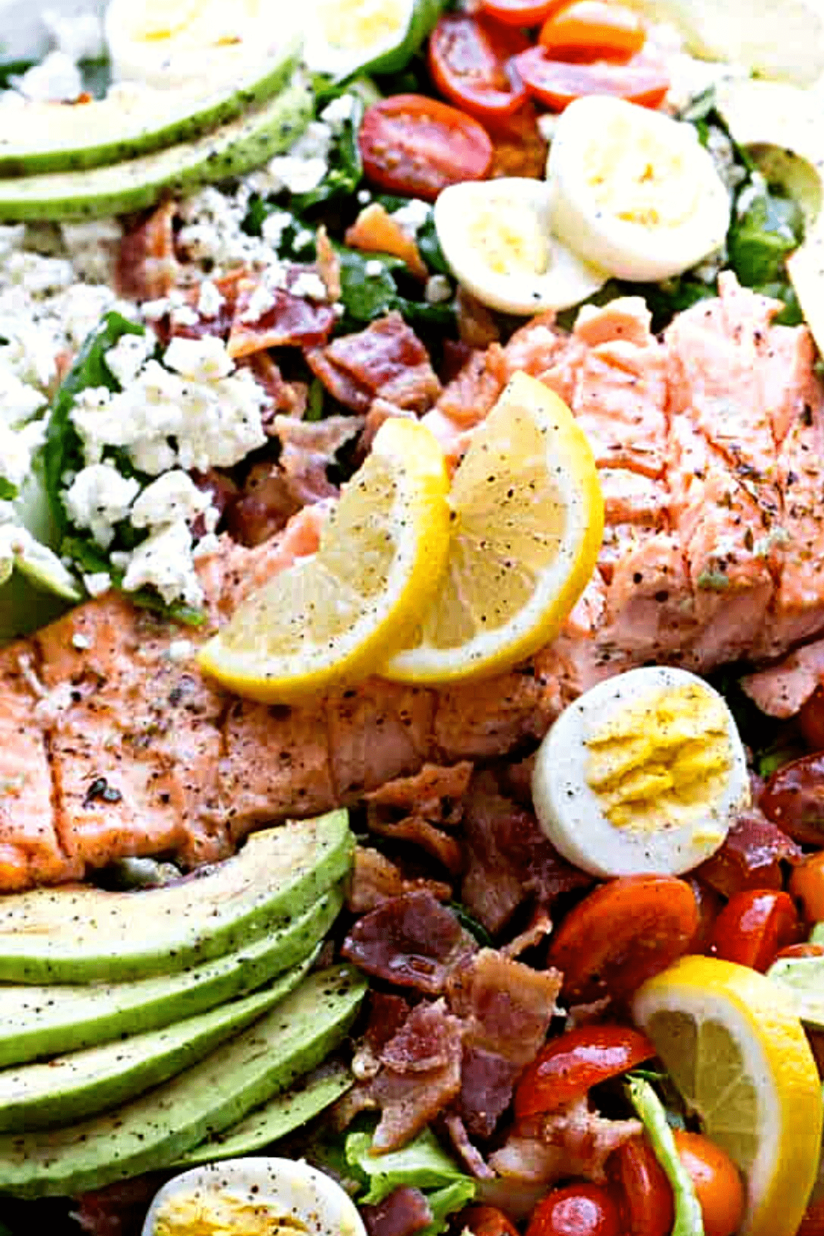 Salmon Cobb Salad with Spinach and Feta - Tender spinach and romaine lettuce topped with delicious oven-baked salmon, tomatoes, eggs, bacon, avocados and feta, all tossed together with a tangy lemon-mustard dressing.