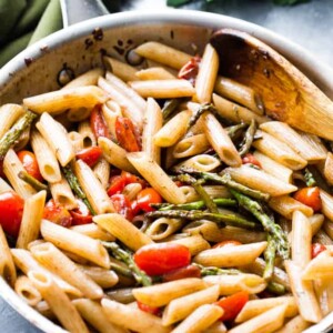 Balsamic penne pasta with asparagus and tomatoes in a pan.