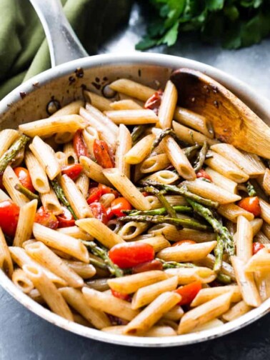 Balsamic penne pasta with asparagus and tomatoes in a pan.