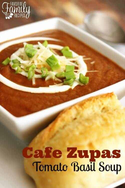 A bowl of Cafe Zupas Tomato Basil Soup with a swirl of cream, shredded cheese, and scallions
