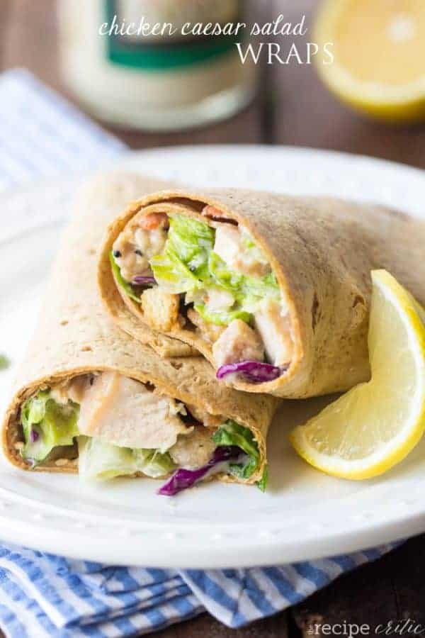 Two halves of Chicken Caesar Salad Wraps stacked on a plate with a lemon wedge