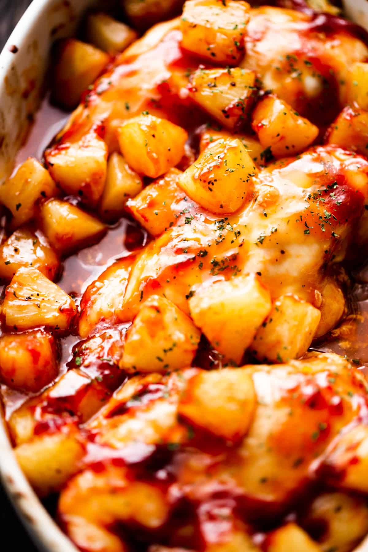 Juicy baked barbecue chicken breasts topped with pineapple in a baking dish.