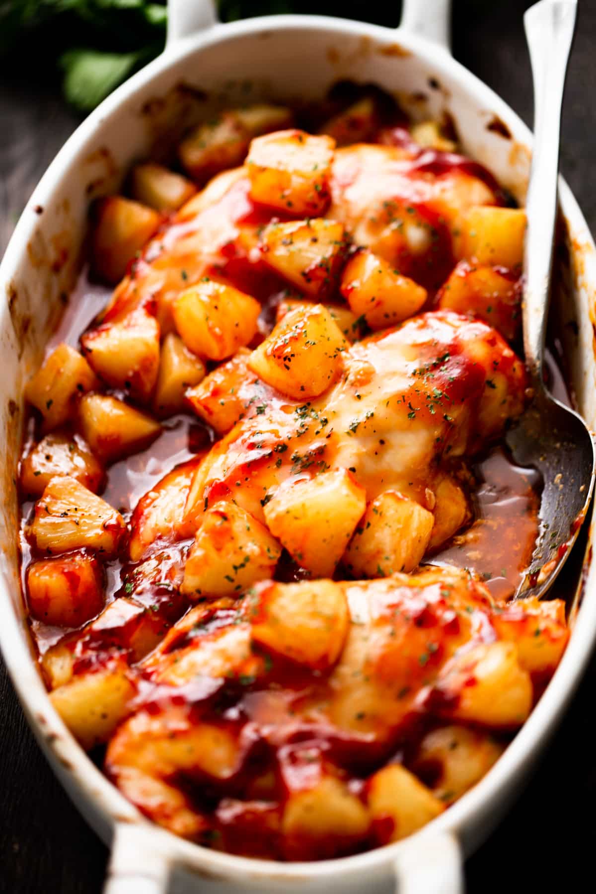 overhead shot of an oval dish with three chicken breasts topped with chunks of pineapple and smothered with barbecue sauce.