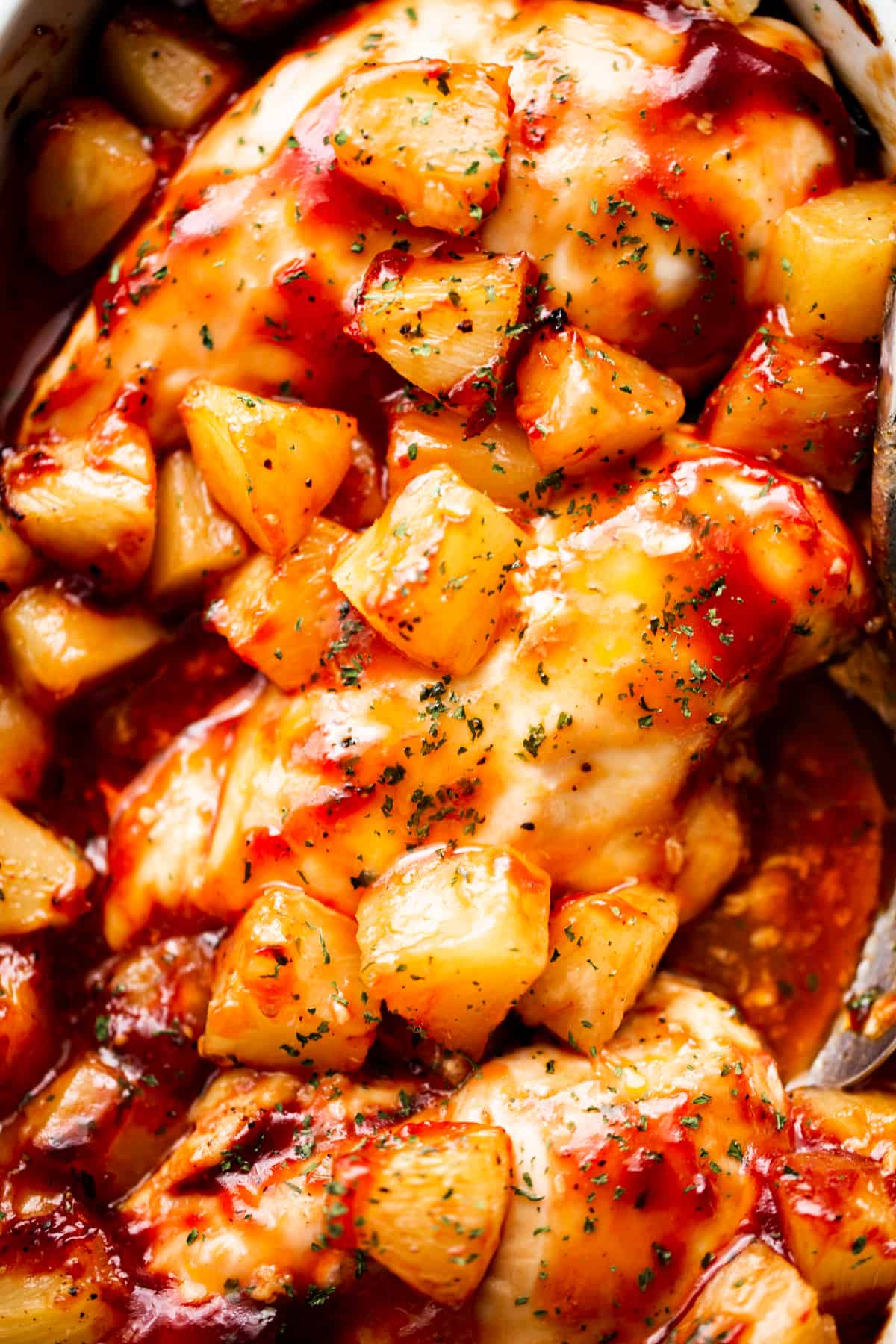 close up shot of three chicken breasts topped with chunks of pineapple and smothered with barbecue sauce.