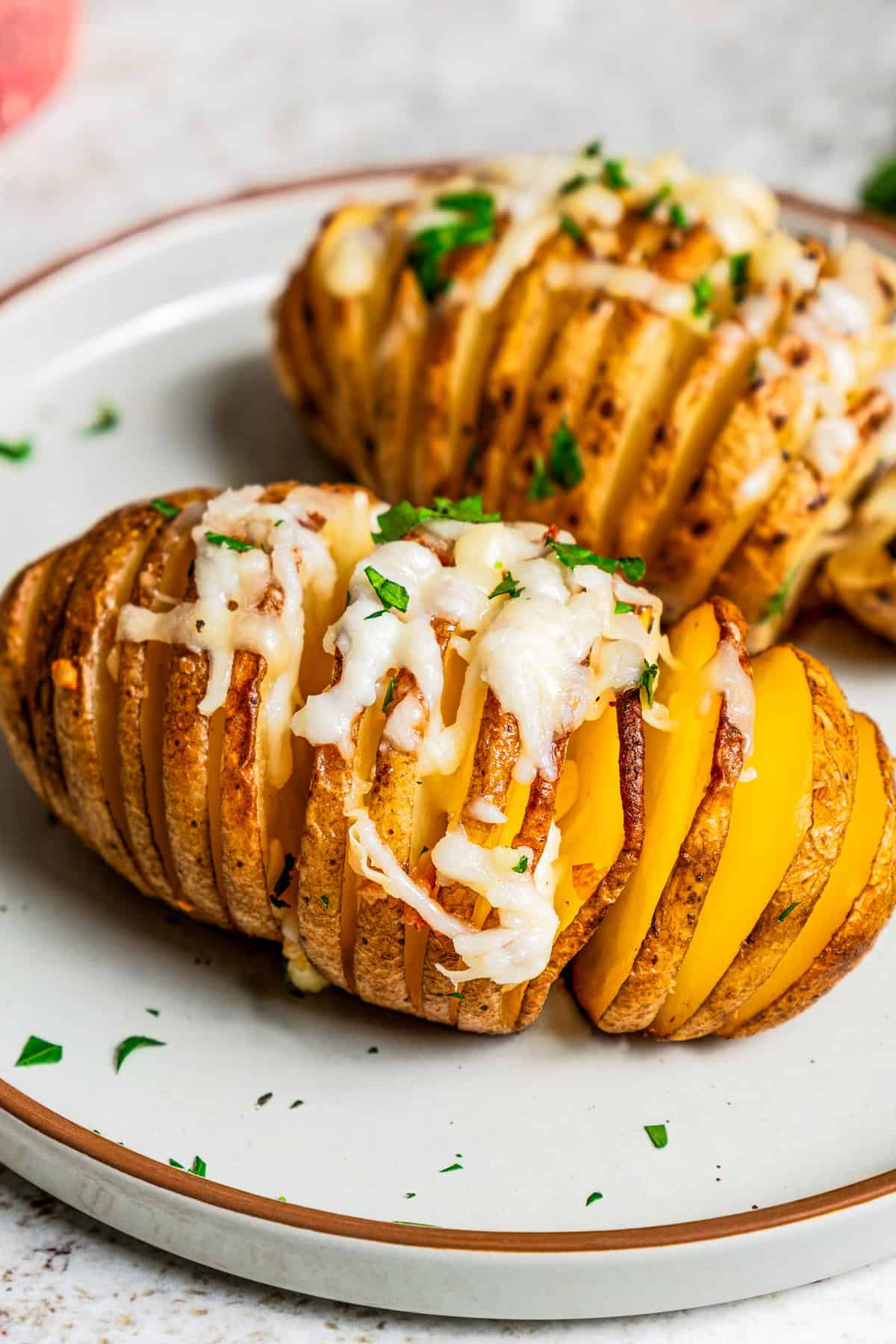 Two hasselback potatoes served on a dinner plate.