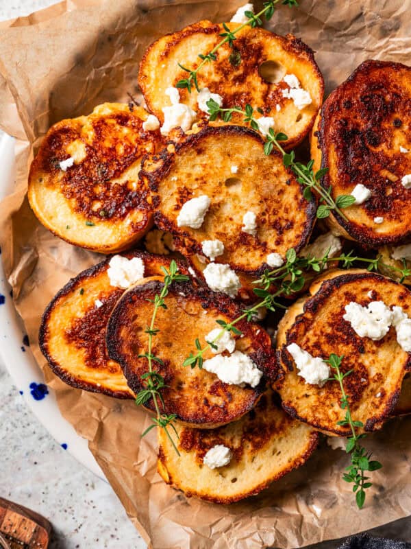 Slices of French toast topped with crumbled feta and thyme and served on a parchment-lined platter.