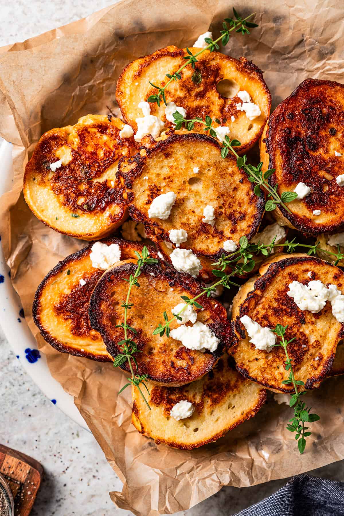 Slices of French toast topped with crumbled feta and thyme and served on a parchment-lined platter.