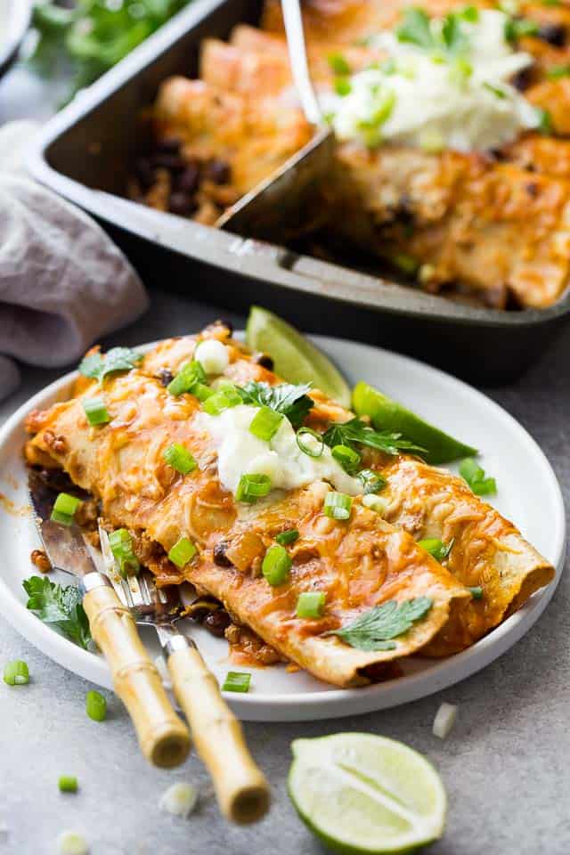 Two turkey enchiladas served on a white dinner plate.