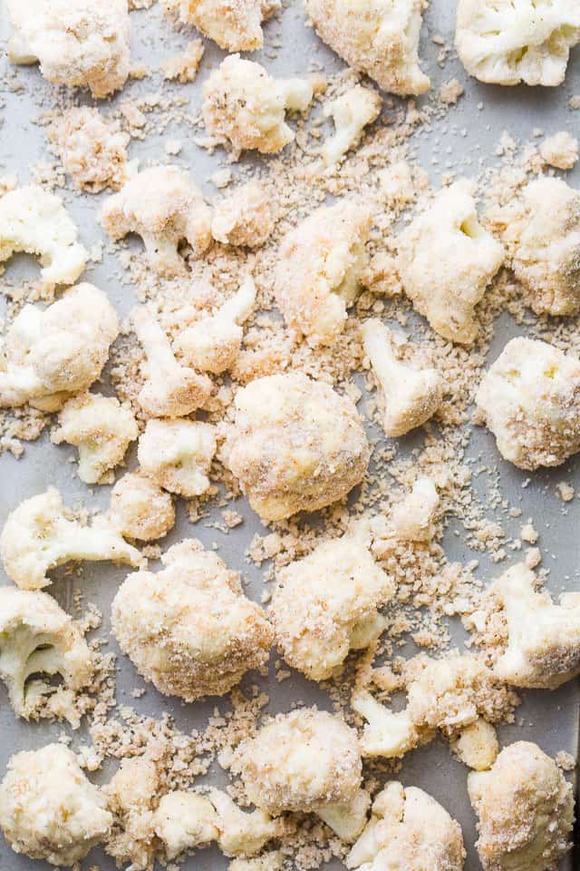 Cauliflower florets, breaded and arranged on a gray-colored background.