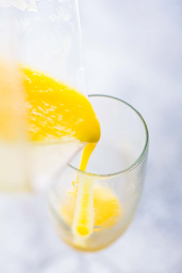 Pouring a mango puree in a flute glass.