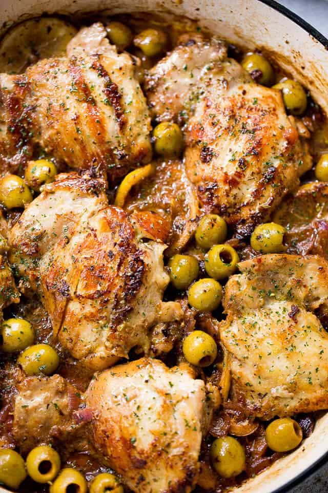 Close-up photo of Chicken thighs with Lemons and Olives arranged around the chicken.