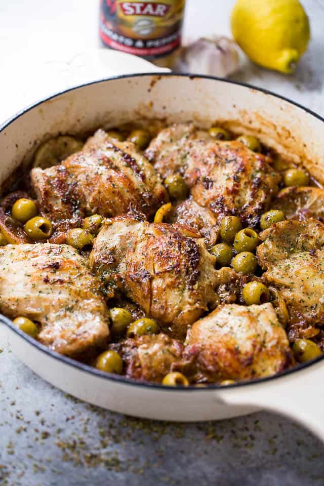 Chicken thighs in a skillet with Lemons and Olives.