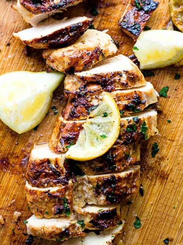 Sliced grilled chicken on a cutting board.