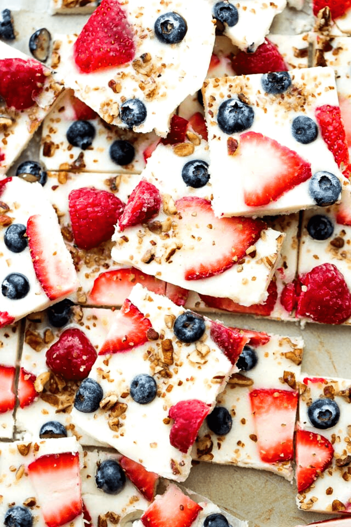 Frozen yogurt topped with blue and red berries and broken into squares.