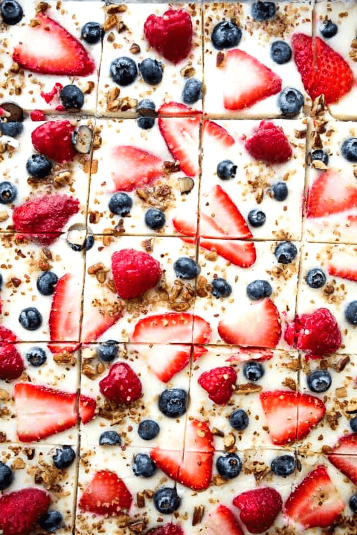 Yogurt bark topped with blue and red berries and broken into squares.
