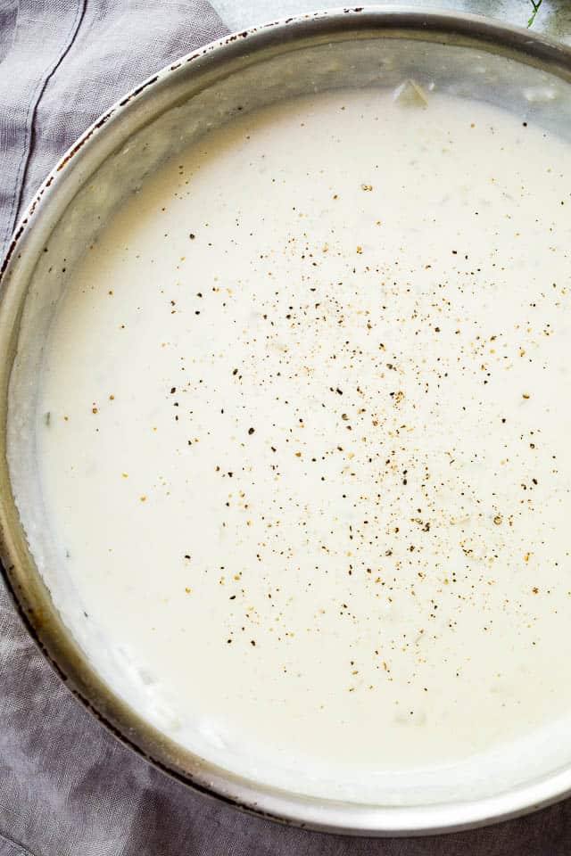 Pot of cream sauce with seasoning.