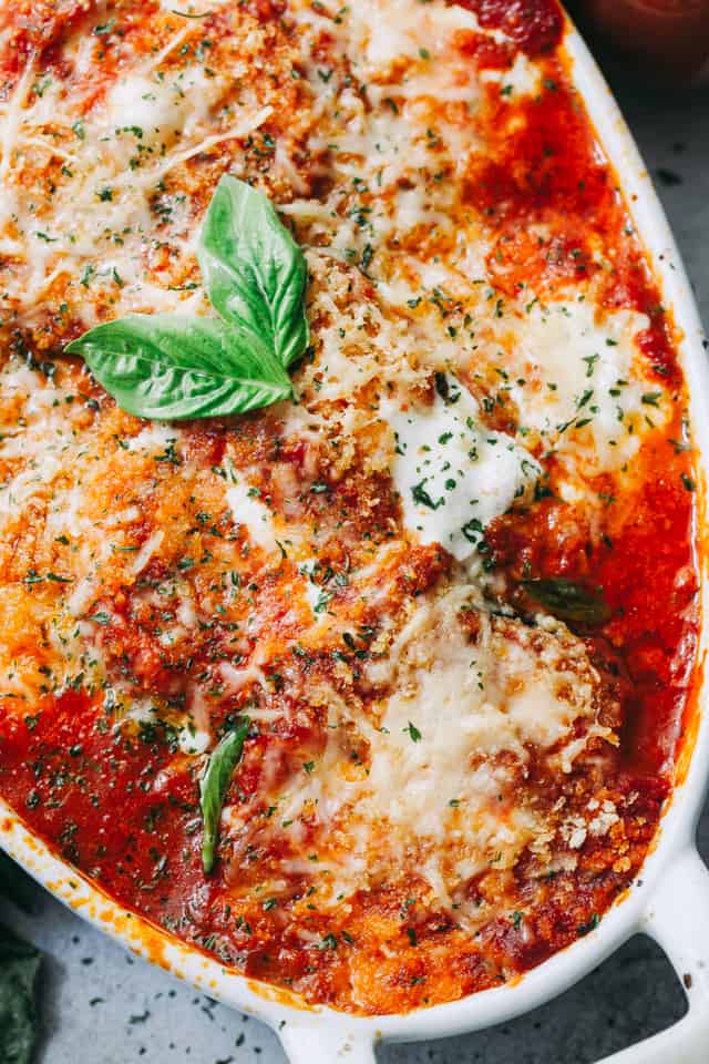 Close-up shot of cheesy Eggplant Parmesan garnished with fresh basil leaves.