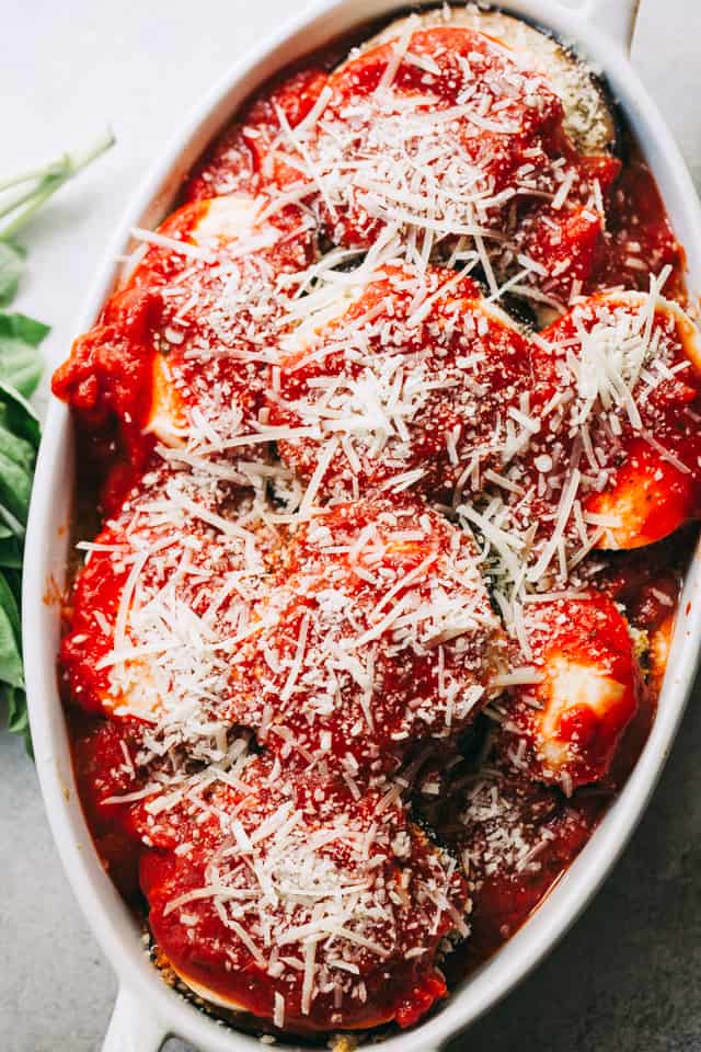 Baking dish with eggplants topped with tomato sauce and a sprinkle of freshly grated parmesan cheese.