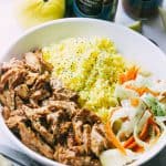 A bowl of tandoori chicken served with rice and a cucumber and carrot salad.