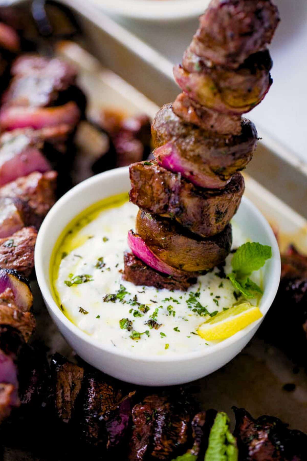 Dipping a steak skewer into a creamy dip.