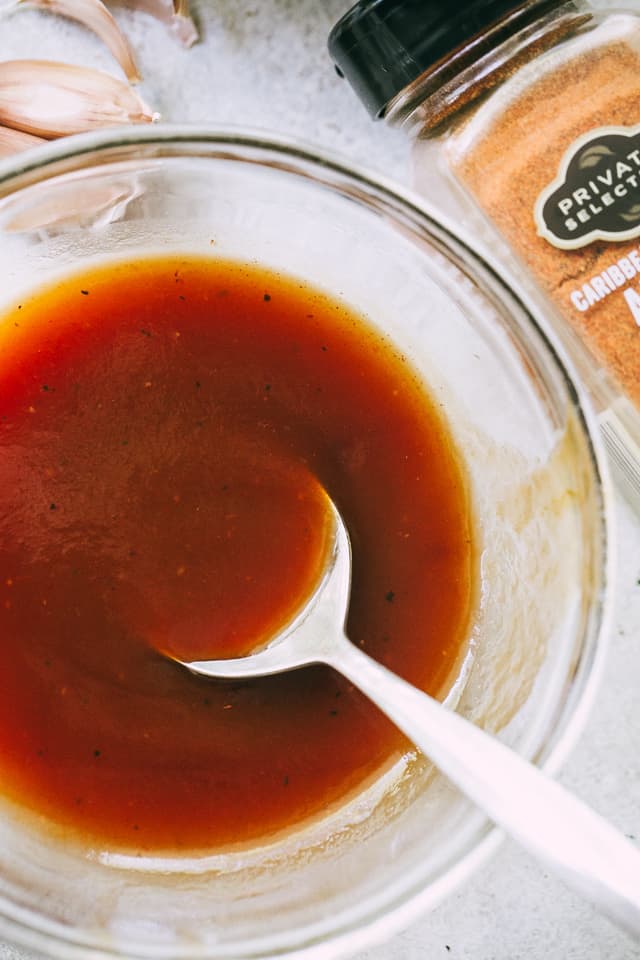 Golden-brown homemade barbecue sauce in a bowl with a spoon in it.
