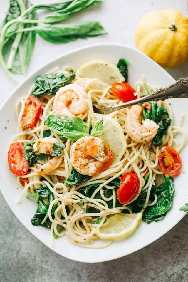 This lemon shrimp spaghetti is an easy 30-minute dinner with juicy shrimp, tomatoes, spinach, garlic, and plenty of fresh lemon flavor. Lemon shrimp spaghetti with spinach, tomatoes, fresh basil, and lemon wedges served in a white bowl.