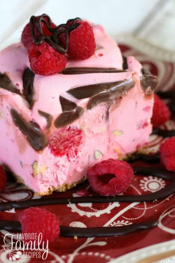 A slice of Raspberry Almond Fudge Ice Cream Cake on a plate garnished with fresh raspberries