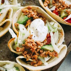 Taco Bowls - Fun and delicious baked flour tortilla bowls filled with taco-seasoned ground turkey meat, salad, tomatoes, cheese, and topped with a dollop of sour cream!