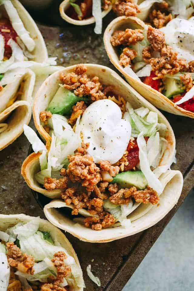 Overhead view of Taco Bowls filled with taco-seasoned ground turkey meat, salad, tomatoes, cheese, and topped with a dollop of sour cream