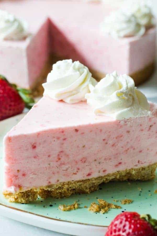 A slice of strawberry frozen yogurt pie with graham cracker crust and whipped cream