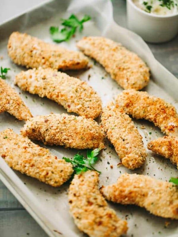 Baked chicken tenders arranged in a single layer on a baking sheet.