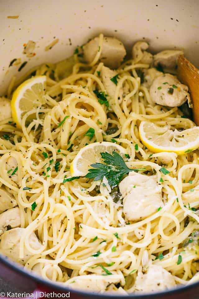 Close-up of spaghetti with diced chicken, capers, sliced lemon and parsley