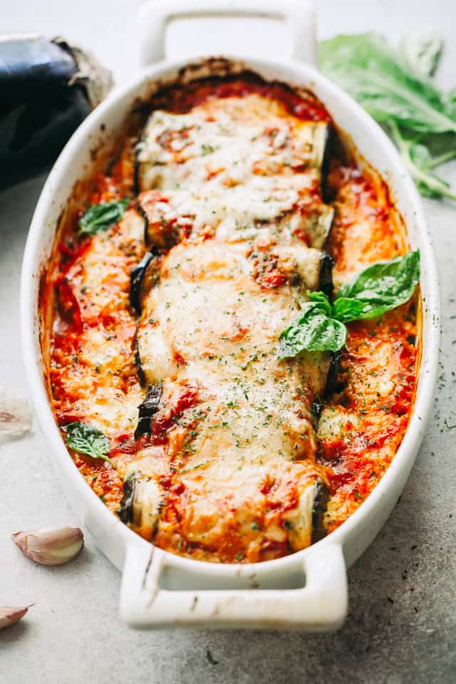 Baked Eggplant rollups stuffed with a cheesy ricotta blend and arranged in a baking dish.