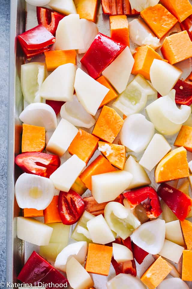 Cubes of Butternut squash, potatoes, peppers, and onions spread out on a baking sheet.