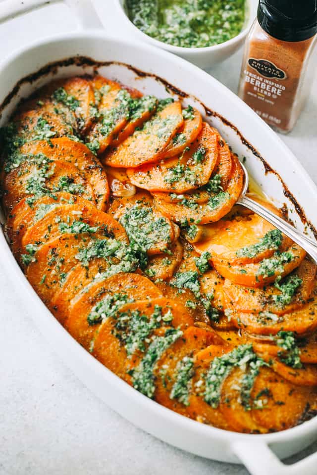 Sweet Potato Roast with Parsley Pesto in an oval casserole dish with a spoon 