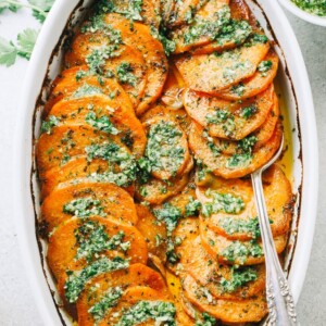 Sweet potatoes fanned out in a baking dish and topped with parsley pesto.