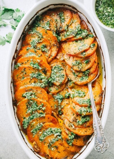 Sweet potatoes fanned out in a baking dish and topped with parsley pesto.