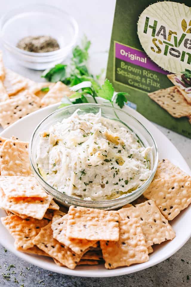 A bowl of creamy artichoke dip served with crackers.