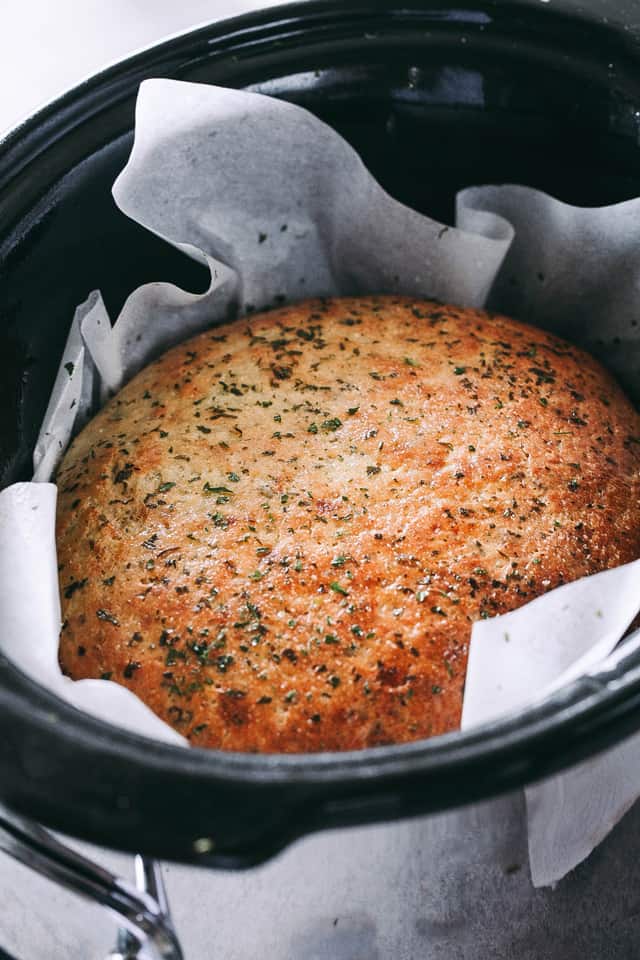 A loaf of baked bread inside a slow cooker.